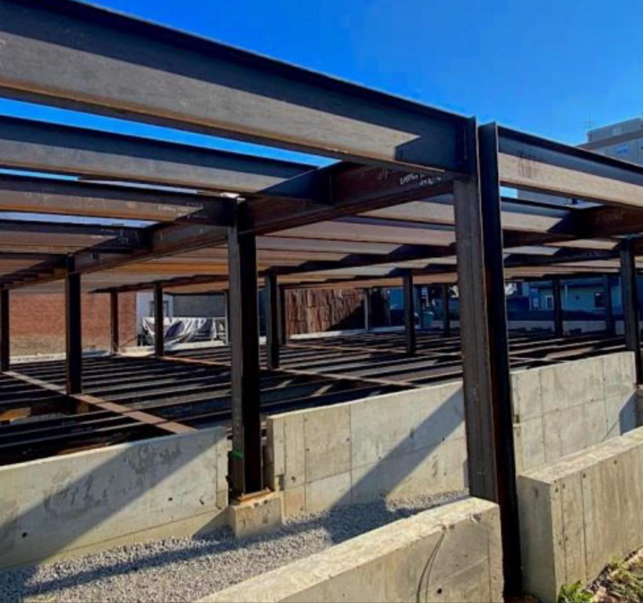 Structural steel frame erected above concrete foundation walls